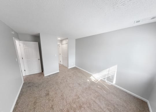 the living room of an apartment with a carpeted floor and white walls