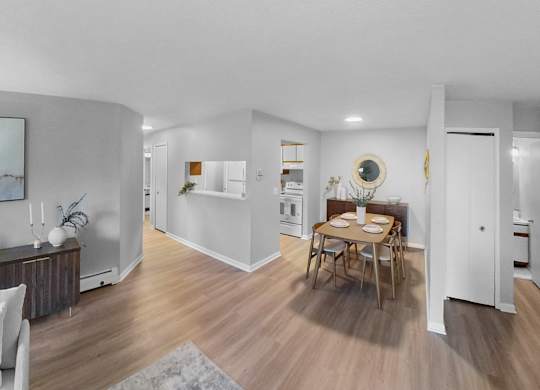 a living room and dining room with white walls and wood floors