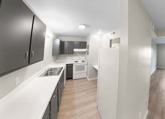 an empty kitchen and living room with white counter tops and wood floors