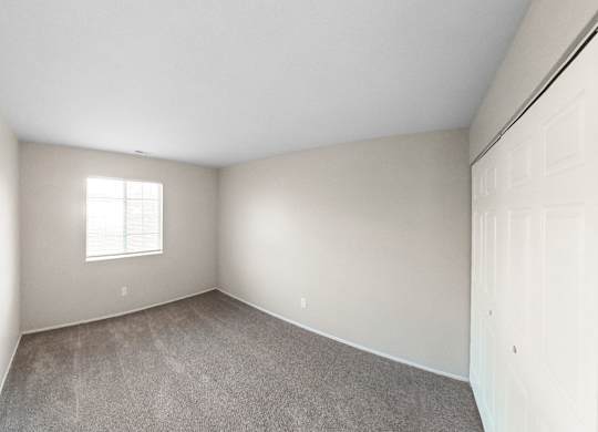 an empty bedroom with white walls and a window
