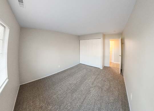 an empty bedroom with a carpeted floor and a door to a closet