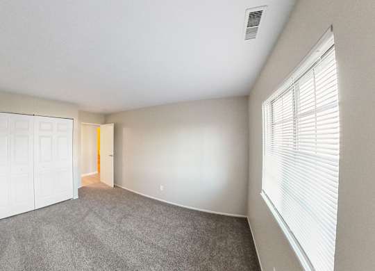 an empty living room with a large window and a white door