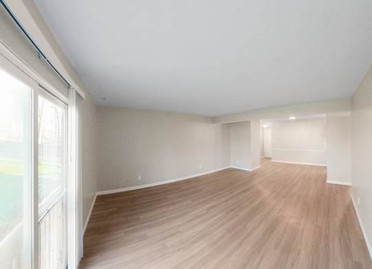 an empty living room with wood flooring and a large window