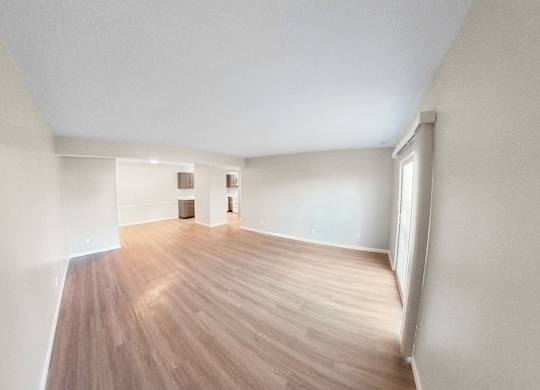an empty living room with wood flooring and white walls