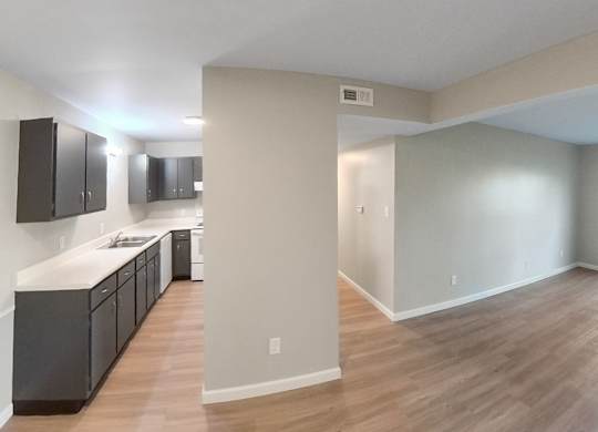 an empty living room and kitchen with wood flooring and a window
