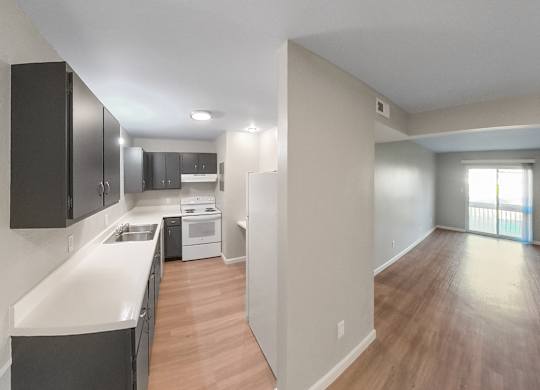 an empty kitchen and living room with wood flooring and a window