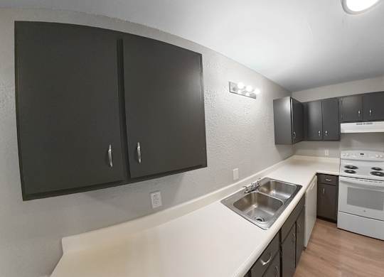 an empty kitchen with black cabinets and white appliances