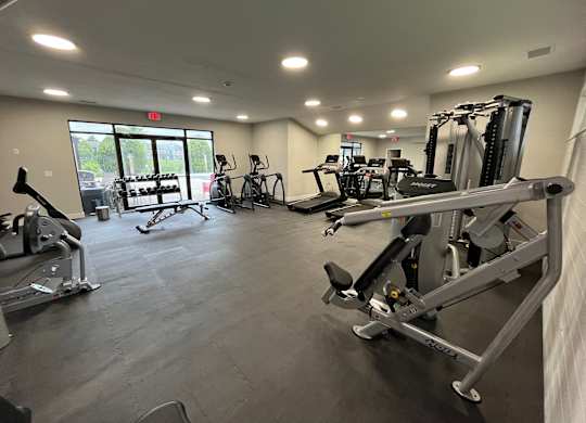 A gym with a variety of exercise equipment including treadmills, stationary bikes, and weight machines.