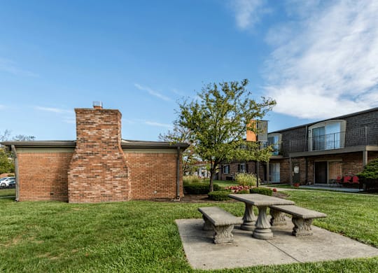 a picnic area with a stone bench in front of a brick building