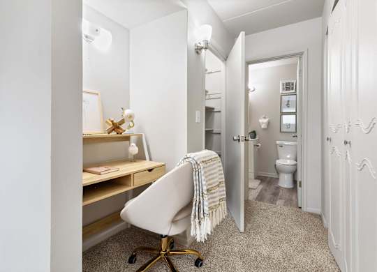 a bedroom with a desk and a chair and a bathroom with a toilet