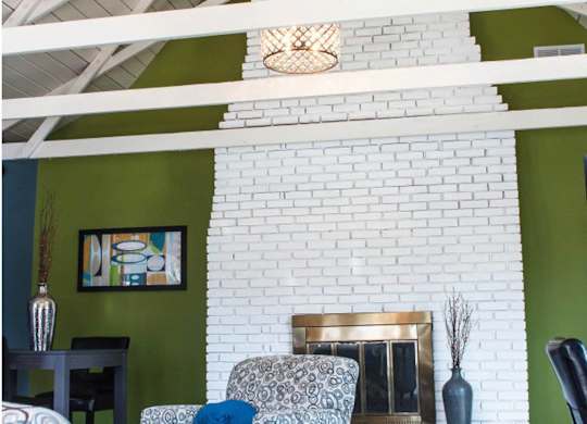 a living room with a white brick fireplace and green walls
