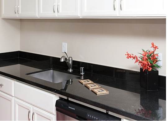 A kitchen with black countertops and white cabinets.