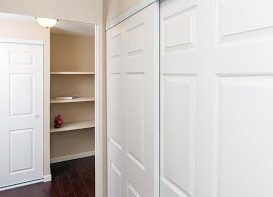 A white door is open to a hallway with a shelf and a pair of red shoes on it.