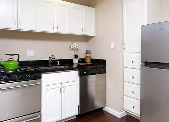 A kitchen with white cabinets and a black countertop.