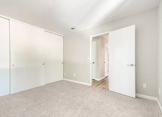 A white room with a carpeted floor and a white door.