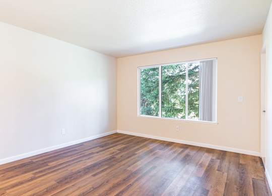 Empty room with wooden floors and a window.