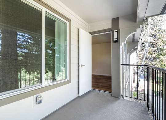 A balcony with a sliding glass door and a black railing.