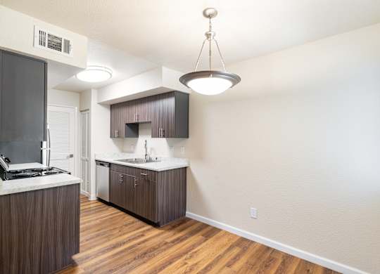 A kitchen with wooden floors and a white wall.