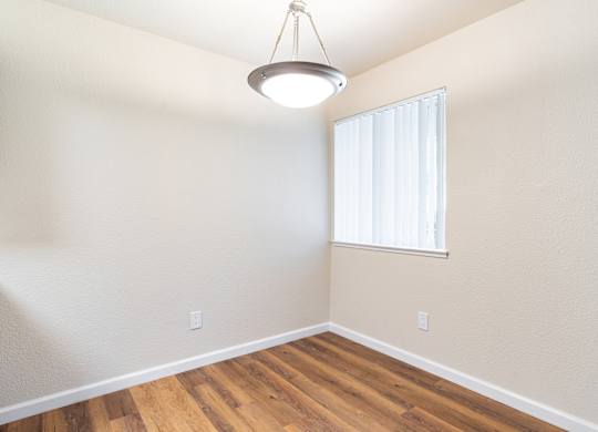 A room with a window and a wooden floor.