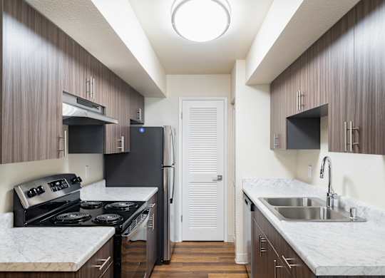 A kitchen with a white counter top and dark wood cabinets.
