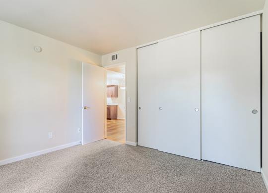 A white room with a carpeted floor and a white door.