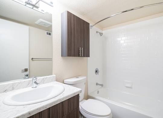 A white sink is on a marble countertop in a bathroom.