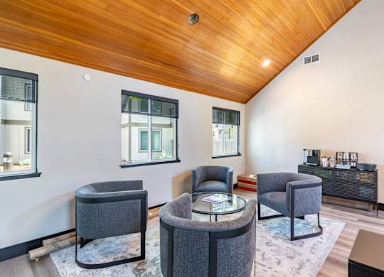 A living room with a wooden ceiling and grey chairs.