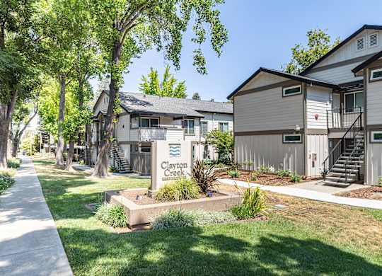 A row of houses with the name Clayton Creek on a sign in front.