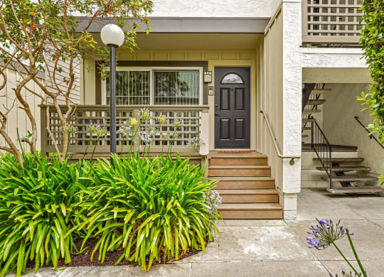 the front of a house with stairs and a black door