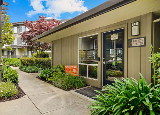 the entrance to an office building with a sidewalk and plants