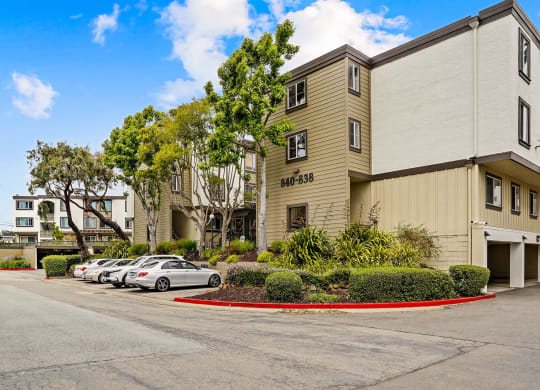 a street view of an apartment building with cars parked in front