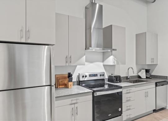 A modern kitchen with stainless steel appliances and white cabinets. at Paperbox Lofts, Salt Lake City, UT, 84101
