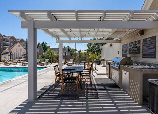 a patio with a grill and a table with chairs and a pool at City View St. George Apartments, St George, UT, 84770