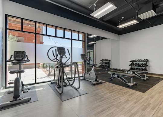 a gym with weights and other exercise equipment and a large window at City View St. George Apartments, St George, UT