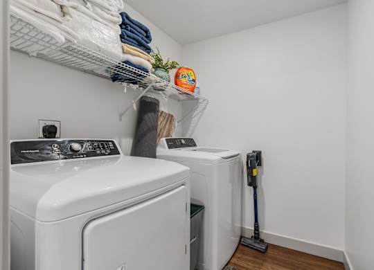a washer and dryer in a small laundry room with white walls and wood at City View St. George Apartments, St George, Utah