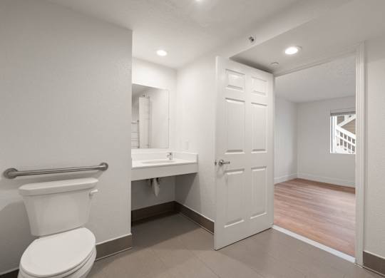 A white toilet is in a small bathroom with a white door at AVIA Lofts on Parkway Apartments, Washington, 98662