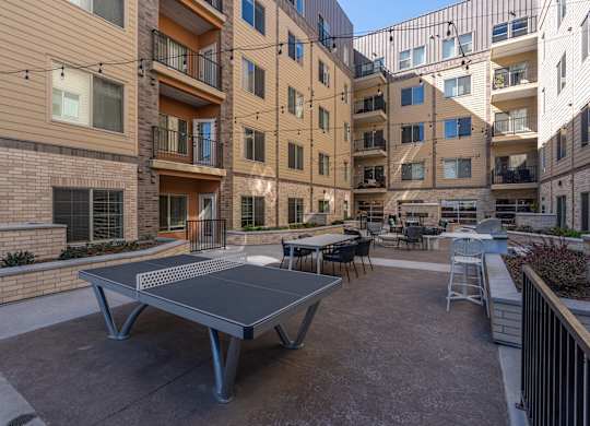 a patio with a ping pong table in front of an apartment building at The Revival, Salt Lake City, UT