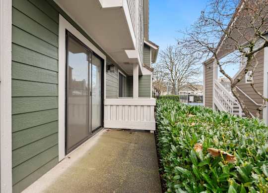 A green house with a white fence and a glass door. at AVIA Lofts on Parkway Apartments, Vancouver
