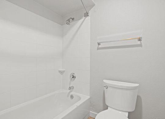 a white bathroom with a tub and a toilet at AVIA Lofts on Liberty Ridge Apartments, Jacksonville, FL, 32256