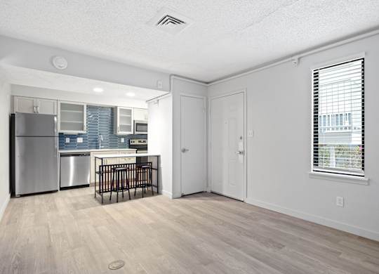the living room and kitchen of an apartment with a crib and a refrigerator at AVIA Lofts on Liberty Ridge Apartments, Jacksonville, FL, 32256