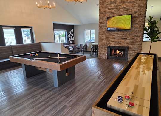 Community room with a pool table and a TV mounted above a fireplace at Avia Lofts at Maple Road, Amherst, 14221