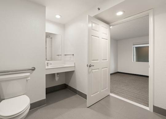 A white toilet is in a small bathroom with a white sink and a white door at AVIA Lofts on Parkway Apartments, Vancouver, WA, 98662