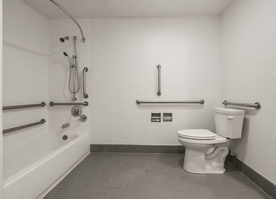A white toilet in a bathroom with a shower head and hand held shower at AVIA Lofts on Parkway Apartments, Vancouver, WA, 98662