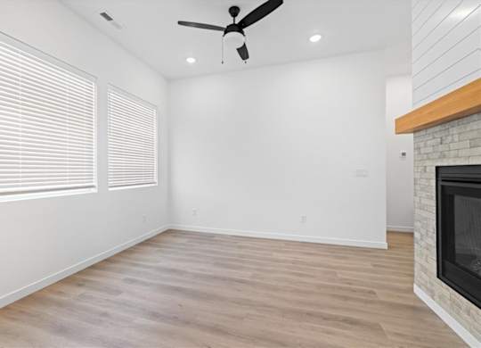 A room with a fireplace and a ceiling fan.at Alante Homes at Spring Run, Caldwell, 83607