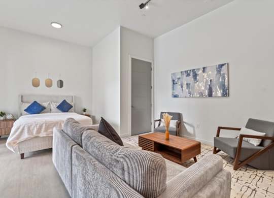A modern bedroom with a large bed and a grey couch. at Paperbox Lofts, Salt Lake City, 84101