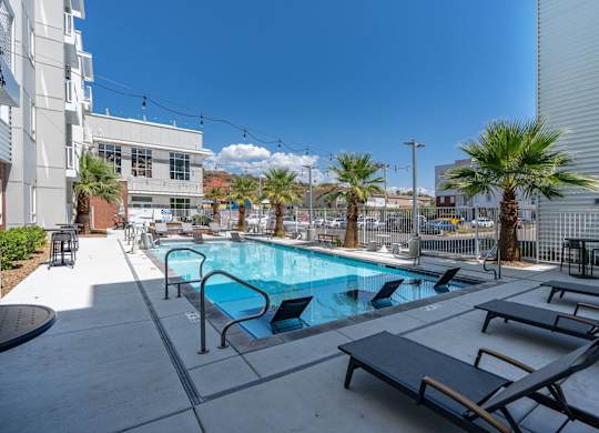 a swimming pool with lounge chairs and palm trees in front of a building at 605 Place Student Housing & Co-Living, St George, Utah