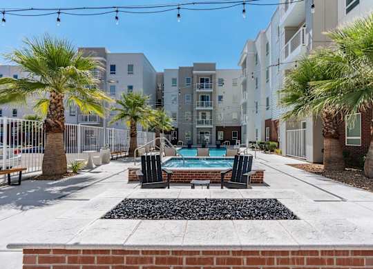 an outdoor patio with a pool and palm trees in front of an apartment building at 605 Place Student Housing & Co-Living, St George, Utah