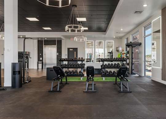 a fitness room with weights and chairs and a large window at 605 Place Student Housing & Co-Living, St George