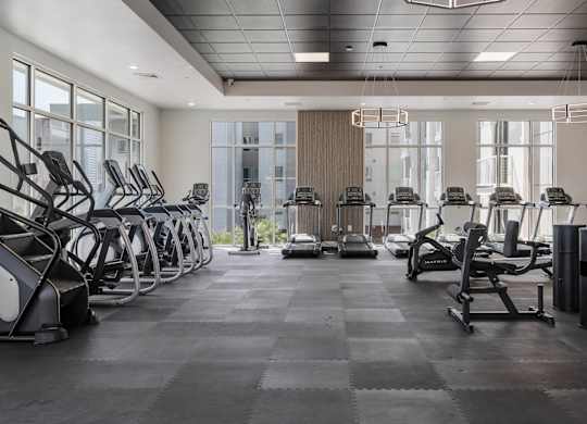 a large fitness room with cardio equipment and windows at 605 Place Student Housing & Co-Living, St George, UT