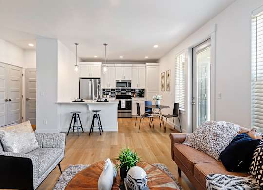 a living room and kitchen area with white walls and hardwood floors at Alante Homes at Lake Hazel, Boise, ID, 83709